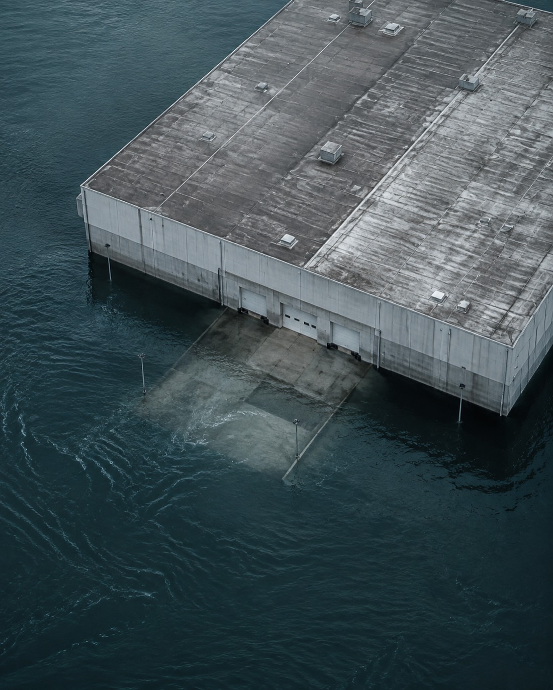 Floodwater surrounding a distribution warehouse, submerging its loading area.